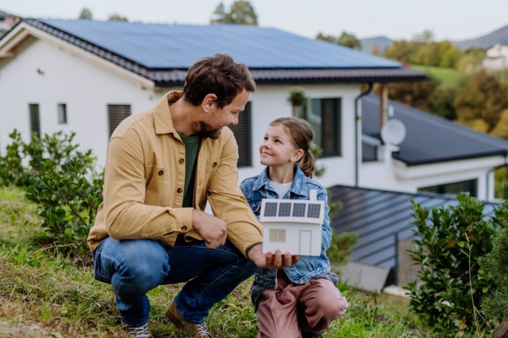 Vater und Tochter mit Modell eines Hauses mit Photovoltaikanlage in Moers